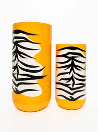 Un vase moderne pour bouquet de fleurs au style tropical avec un dessin peau de bête sauvage noir, blanc et orange.